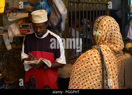 STONE Town, Zanzibar, Tanzanie - 06 juillet 2008 : Forfaits de prendre une note. Une transaction entre un homme et une femme dans un marché à Stone Town, Zanzibar. Banque D'Images