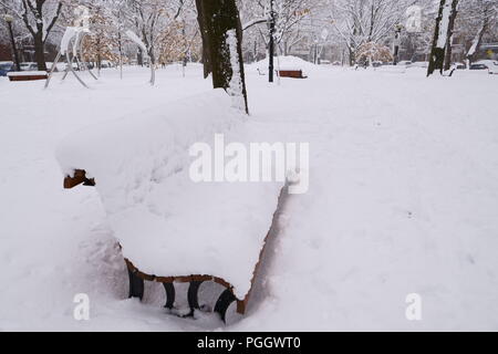 Première neige est tombée sur tout pendant la nuit. Un banc de parc est couverte de neige dans un parc public. Banque D'Images