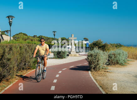 Homme mûr (55) cycles le long d'une piste cyclable, près de Praia do Guincho et Roca Cabo près de Cascais, Portugal pendant un jour d'été Banque D'Images