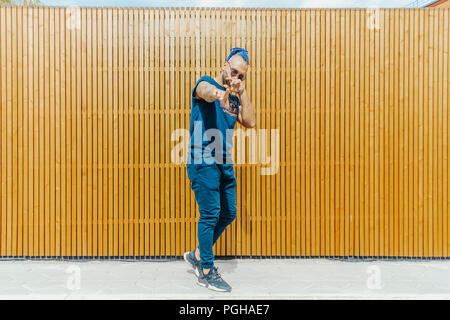 Jeune homme avec des dreadlocks bleu reggaeton danse dans la rue. L'homme est sur le point de mire et de premier plan, arrière-plan est flou. Banque D'Images