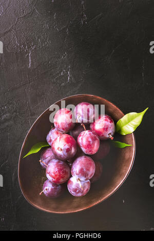 Bleu Violet rouge frais entiers et les prunes coupées en tranches avec un couteau bol sur une table de cuisine Banque D'Images