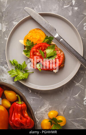 Sandwich avec tomates et fromage sur la plaque grise, vue du dessus. Concept de l'alimentation propre. Banque D'Images