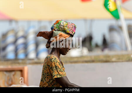 OUIDAH, BÉNIN - Jan 10, 2017 : femme non identifiés dans les vêtements clairs béninois et voile promenades sur la rue. Bénin Les gens souffrent de la pauvreté en raison de Banque D'Images