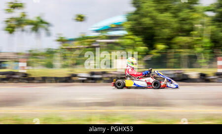 Un coureur professionnel avec combinaison de course de kart dans sa ville à la compétition de karting piste de course sous un temps chaud, tourné avec la caméra panoramique vers Banque D'Images