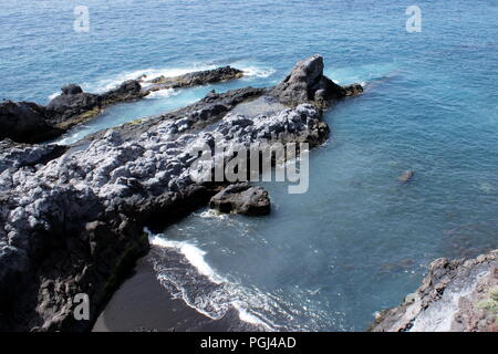 Ténérife, Sain. Vue sur une petite baie formée de roches volcaniques, près de la spectaculaire ville balnéaire de Los Gigantes. Les vagues de l'Atlantique se brisent sur le bord de mer. Banque D'Images