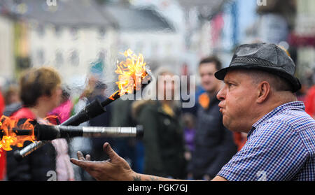 Ballycastle, Irlande du Nord. Lundi 27 Août, 2018. Un artiste de rue jongle avec des torches enflammées à l'Ould Lammas Fair à Ballycastle Le Ould Lammas Fair est la plus ancienne foire de l'Irlande. Le mot Lammas vient de 'la masse' - Pain pain cuit traditionnellement à partir de la première les grains d'automne ont été mis sur l'église à modifier. SSince le 17ème siècle, l'traders affluent sur la juste d'acheter et de vendre des animaux, une tradition qui continue Crédit : Graham de Alamy Live News Banque D'Images