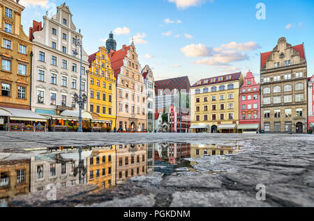 Vieux bâtiments colorés se reflétant dans une flaque d'eau sur la place Rynek à Wroclaw, Pologne Banque D'Images