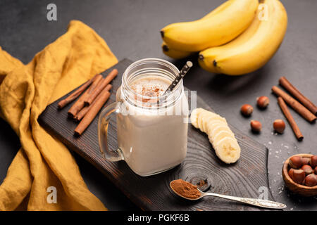 Smoothie banane avec cannelle en verre sur fond sombre. Selective focus Banque D'Images