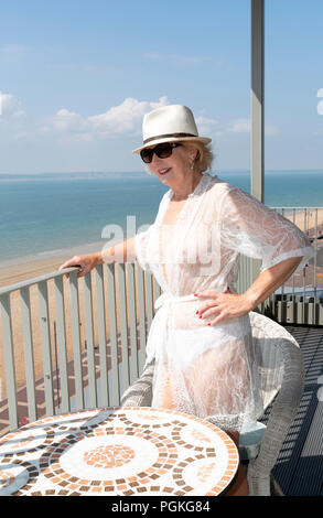 Vieille Femme debout sur un balcon au bord de la mer. Le sud de l'Angleterre, Royaume-Uni Banque D'Images