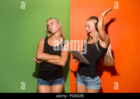 Photo de deux jeunes femmes heureux regardant la caméra et en maintenant les ordinateurs portables à studio. Banque D'Images