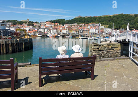 Personnes âgées touristes visiteurs assis sur le banc en été Scarborough Harbour Seafront North Yorkshire Angleterre Royaume-Uni GB Grande-Bretagne Banque D'Images