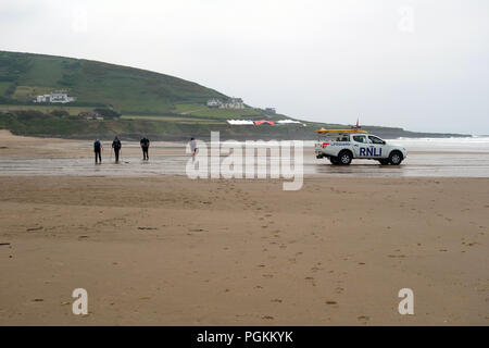 Quatre Randonneurs passant un sauveteur RNLI Véhicule garé sur la plage dans la baie de Croyde sur le chemin côtier du sud-ouest, Devon, Angleterre, Royaume-Uni. Banque D'Images