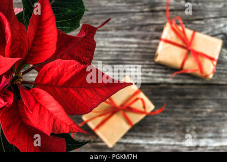 Cadeaux de Noël, enveloppée dans la présente trousse rustique et poinsettia rouge fleur sur fond de bois Banque D'Images