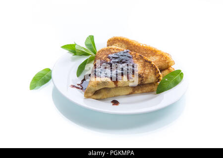 Sweet pancakes mince pliée en forme de triangle avec de la confiture et une feuille de menthe dans une assiette sur un fond blanc Banque D'Images