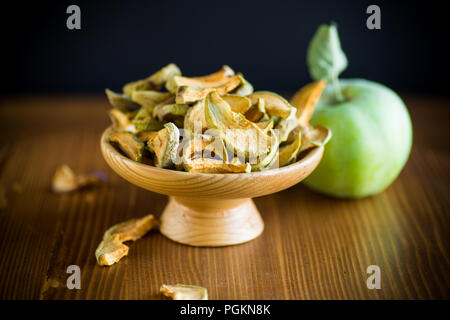 Pommes séchées dans un bol avec une pomme fraîche sur une table en bois Banque D'Images