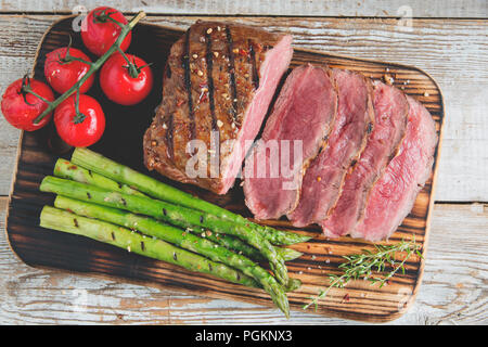 Pavé de boeuf grillé en tranches moyennes rares , les asperges, tomates Banque D'Images