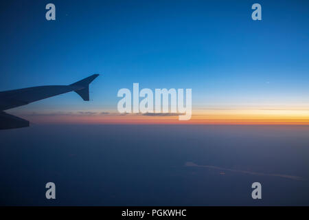 Ailes d'un avion dans le coucher du soleil. Aile d'avion hors de la fenêtre. Banque D'Images