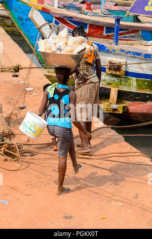 ELMINA, GHANA -Jan 18, 2017 : femme ghanéenne non identifié porte un bassin avec du pain sur la tête à Elmina. Les gens souffrent de la pauvreté du Ghana en raison de t Banque D'Images