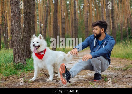 Chien blanc moelleux, debout près de son maître faire du sport Banque D'Images