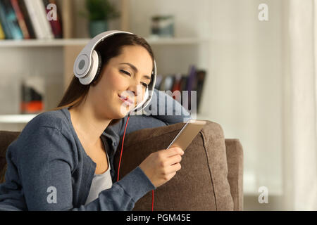 Relaxed woman écouter de la musique assis sur un canapé dans la salle de séjour à la maison Banque D'Images