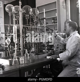 Années 1950, historiques, homme scientifique en blouse blanche travaillant dans un laboratoire avec de nombreux tubes à essai en verre à Oxford univ, pour tester ou investiage réactions gazeuses, Oxford, Angleterre, Royaume-Uni. Banque D'Images