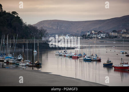 Bateaux amarrés dans le estauary Conway à marée basse comme coucher de soleil. Banque D'Images