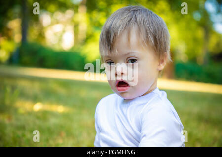 Portrait of Cute petit garçon avec le syndrome de jouer dans la nature Banque D'Images