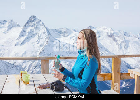 Une femme à l'extérieur de l'eau potable Le surfeur sur un fond de sommets enneigés. Style de voyage concept loisirs actifs en plein air d'hiver Banque D'Images