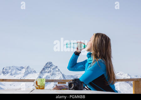 Une femme à l'extérieur de l'eau potable Le surfeur sur un fond de sommets enneigés. Style de voyage concept loisirs actifs en plein air d'hiver Banque D'Images