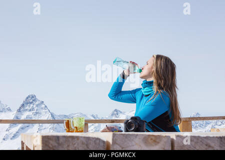 Une femme à l'extérieur de l'eau potable Le surfeur sur un fond de sommets enneigés. Style de voyage concept loisirs actifs en plein air d'hiver Banque D'Images