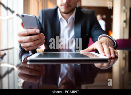 Jeune homme d'affaires travaillant avec les appareils modernes, tablette numérique, ordinateur et téléphone mobile. Banque D'Images