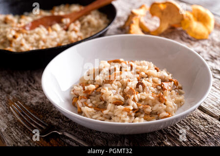 Un bol de délicieux risotto aux girolles sur une table en bois rustique. Banque D'Images