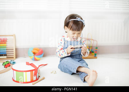 Baby Girl jouer de l'harmonica à la maison Banque D'Images