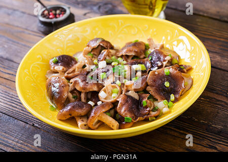 Poêlée de champignons shiitake avec oignon vert sur fond de bois. La cuisine chinoise. Banque D'Images