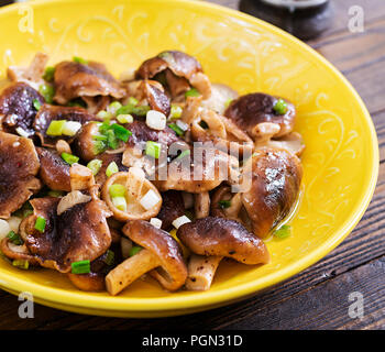 Poêlée de champignons shiitake avec oignon vert sur fond de bois. La cuisine chinoise. Banque D'Images