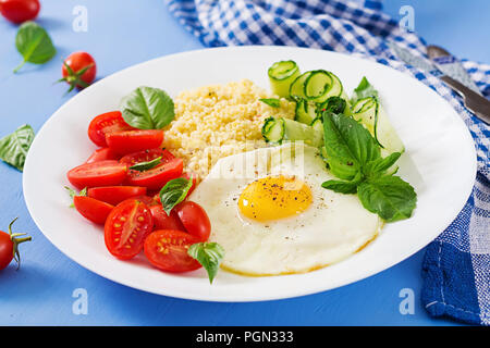 Petit déjeuner sain. Menu diététique. Porridge de millet et de tomates, salade de concombre et d'œufs au plat. Banque D'Images