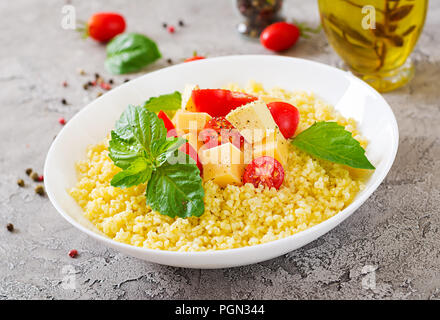 Bouillie de mil avec le fromage, le beurre et le basilic dans un bol blanc. La nourriture bonne. Le petit-déjeuner. Banque D'Images