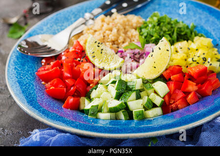Avec Salade de quinoa, roquette, poivrons, tomates et le concombre dans un bol sur un fond sombre. L'alimentation saine, l'alimentation, de désintoxication et végétarienne concept. Buddh Banque D'Images
