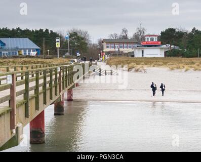 Prerow Allemagne - le 25 janvier 2018 : Deux plongeurs hiver marcher avec leurs engins dans l'eau peu profonde à l'égard de la plage. Banque D'Images