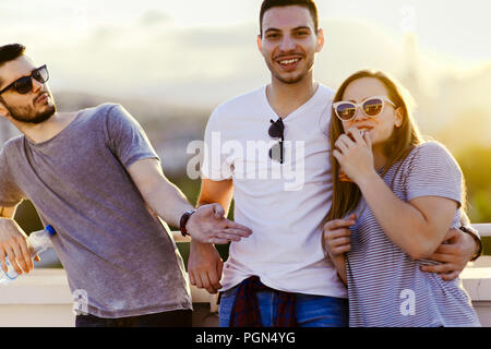 Photo de trois amis en posant sur le toit de l'immeuble au coucher du soleil Banque D'Images