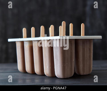 Glace au café sur un bâton dans les moules de plastique sur un fond de bois sombre. Dessert d'été Banque D'Images