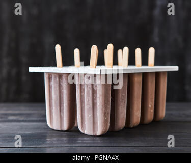 Moules en plastique avec glace au café sur un bâton présenté sur un fond de bois foncé with copy space Banque D'Images