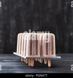 Dessert froid, glace au café sur un bâton dans les moules sur une table en bois foncé avec copie espace. Banque D'Images