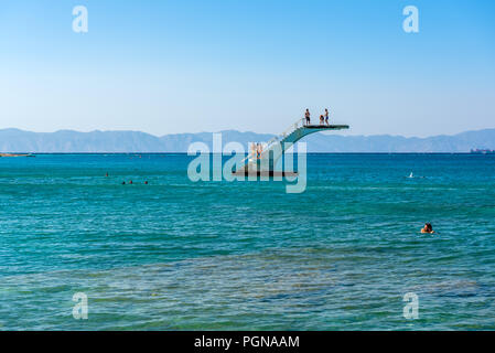 RHODES, GRÈCE - 13 mai 2018 : les jeunes sur une plate-forme de plongée en mer. Plage Elli, la plage principale de la ville de Rhodes. Grèce Banque D'Images