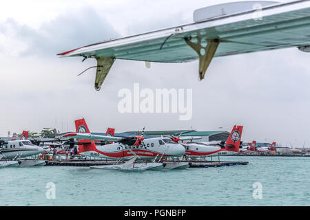 Les Maldives, 10 février 2018 - Un hydravion flottant dans l'eau bleu des Maldives, à proximité d'un pont en bois avec quelques nuages dans le ciel. Banque D'Images