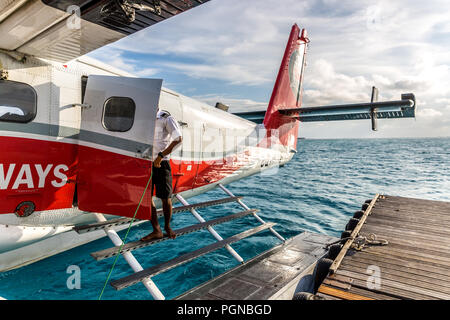 Les Maldives, 10 février 2018 - Un hydravion flottant dans l'eau bleu des Maldives, à proximité d'un pont en bois avec quelques nuages dans le ciel. Banque D'Images