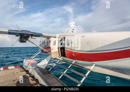 Les Maldives, 10 février 2018 - Un hydravion flottant dans l'eau bleu des Maldives, à proximité d'un pont en bois avec quelques nuages dans le ciel. Banque D'Images