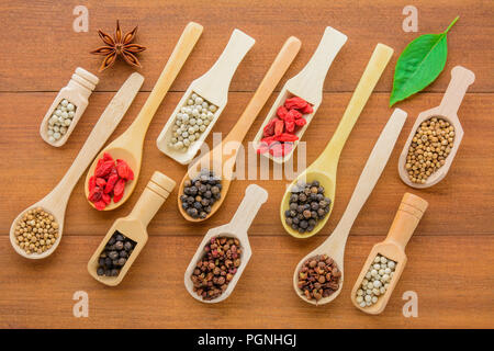 Divers types d'herbes sèches (grains secs) dans la cuillère en bois, différents types d'herbes sèches en cuillère en bois table en bois sur l'espace et de l'alimentation nutrition saine. Banque D'Images