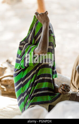 GHANI, GHANA - Jan 14, 2017 : Ghana non identifiés garçon retire son t-shirt vert à rayures dans le village Ghani. Ghana Les enfants souffrent de la pauvreté en raison de Banque D'Images