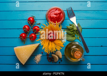 Pâtes avec divers ingrédients pour la cuisine italienne, sur un tableau bleu Banque D'Images